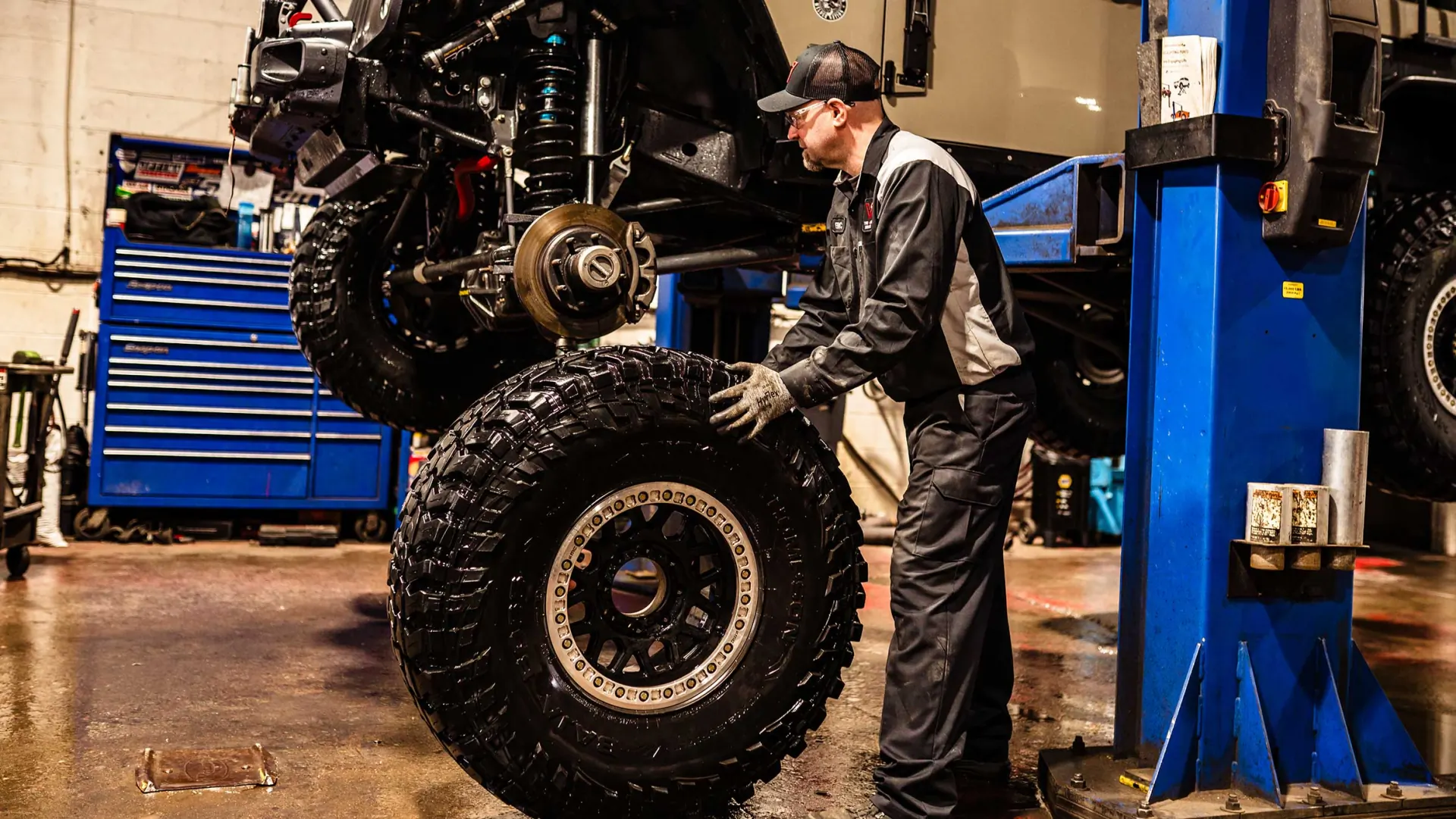 Technician inspecting suspension components under a lifted vehicle
